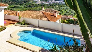 Una piscina con vista a un pueblo y montañas al fondo.