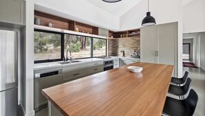 Una cuina moderna amb una illa central, electrodomèstics integrats i vistes cap a l'exterior.
