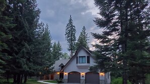 Une maison à deux étages avec une allée en gravier, entourée de grands arbres.