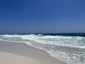 A beach with waves approaching the shore under a clear sky.
