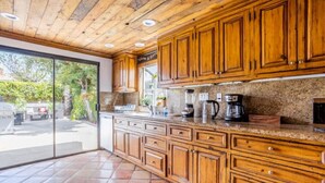 A kitchen with wooden cabinets, a granite countertop, and a view through a glass door. - 5Bed/POOL - Near Hollywood/Burbank/Universal/Beach (Los Angeles)