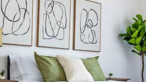 A neatly made bed with a white comforter and green pillows, a bedside table with a small plant, and abstract art on the wall. - 5Bed/POOL - Near Hollywood/Burbank/Universal/Beach (Los Angeles)