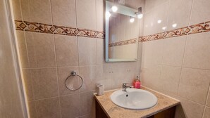 A bathroom with beige tiles, a sink, a mirror, and a towel ring. - Seaside Heaven Apartment (Larnaca)