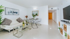 A modern living room with a sofa, coffee table, dining table, chairs, and a TV. - TC-1804 · Lovely 2BR in the Heart of Brickell, Free Parking (Miami)