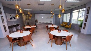 A modern conference room with round tables and orange chairs, large windows, and hanging spherical light fixtures. - TC-1804 · Lovely 2BR in the Heart of Brickell, Free Parking (Miami)