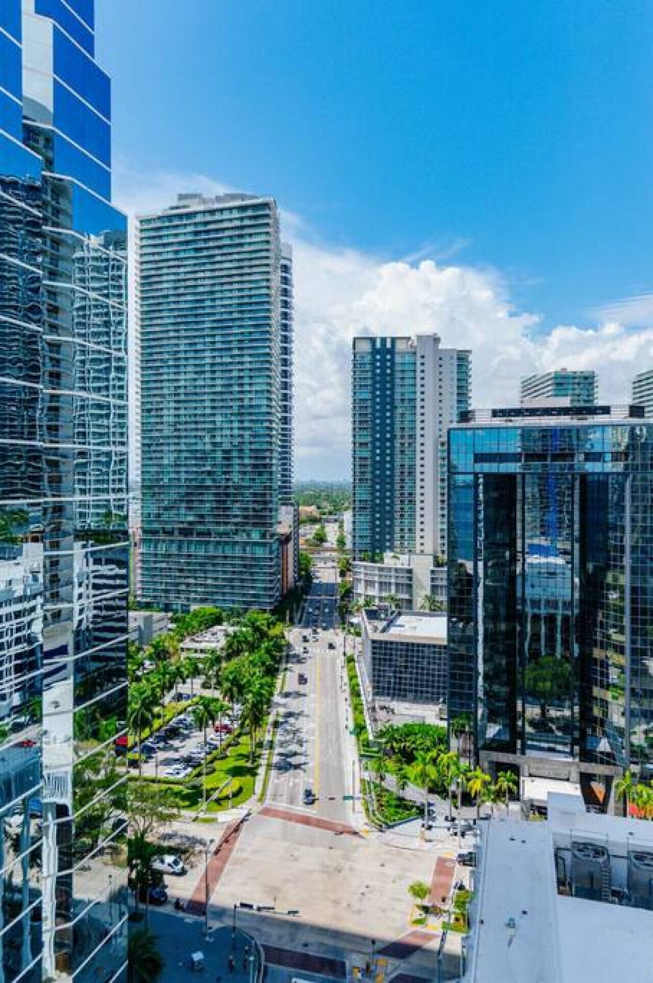 A modern urban area with high-rise buildings, a central road, and green spaces.
