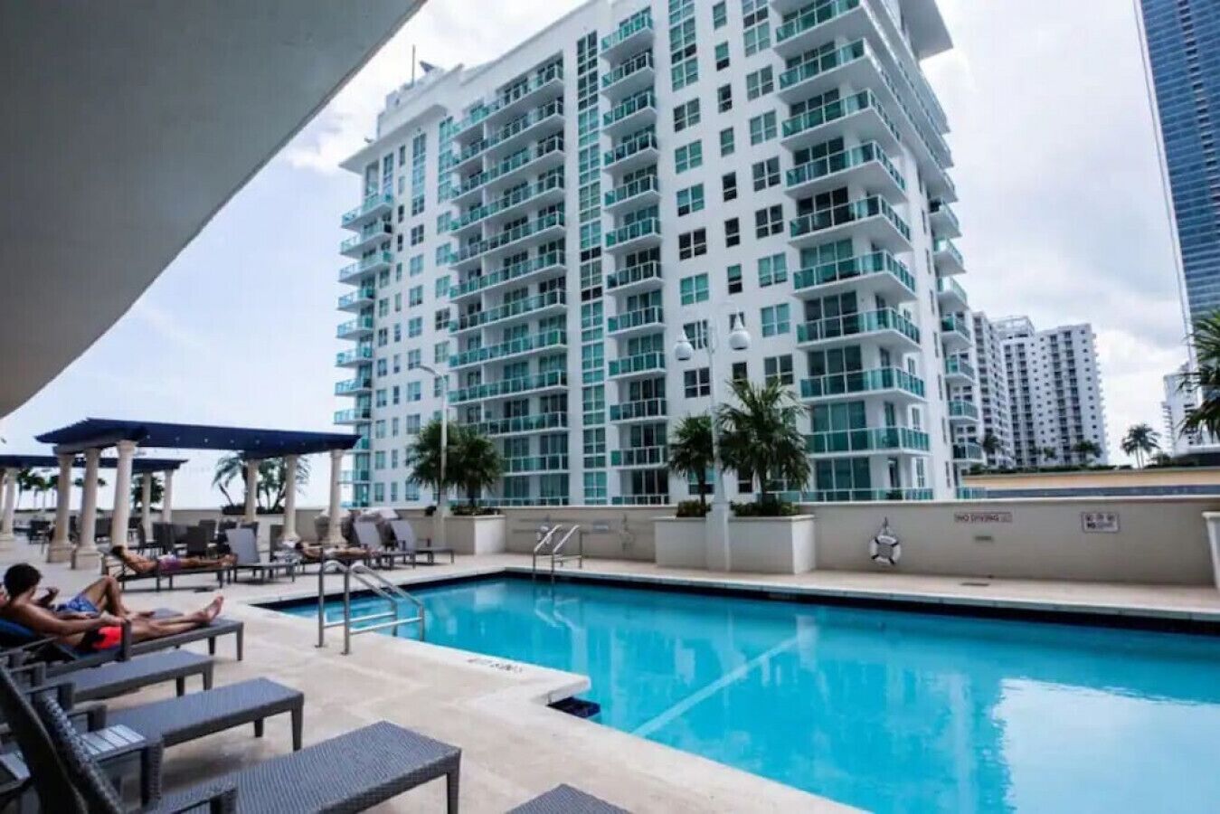 A swimming pool area with lounge chairs and a large building in the background.