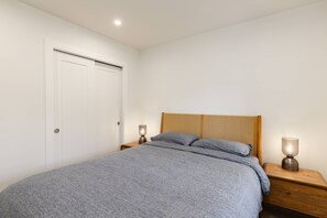 Ein Schlafzimmer mit einem Bett, zwei Nachttischen und einer Tür.