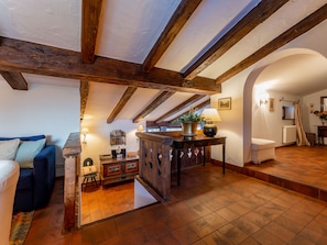 Relax in this inviting space with a comfortable sofa, wooden side table, and potted plant.