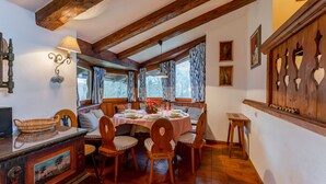 Een eetruimte met een houten tafel gedekt voor vier personen, omringd door houten stoelen.