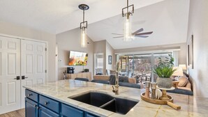 A modern kitchen with a large island, blue cabinets, and pendant lighting.