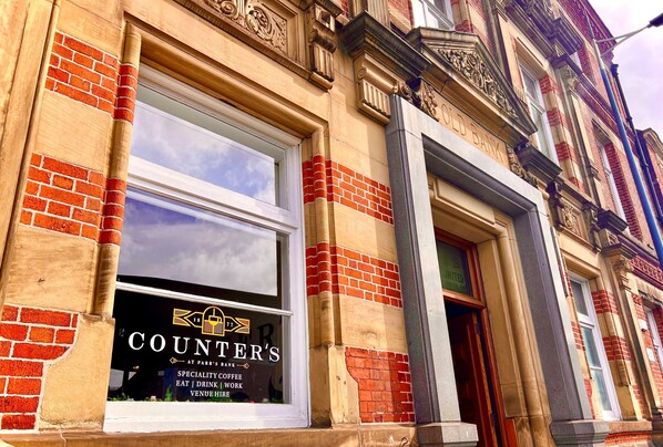 A building facade with a window displaying a coffee shop named 'COUNTER'S' offering specialty coffee, eat, drink, work, and venue hire. - The Parrs Bank Hotel (Warrington)