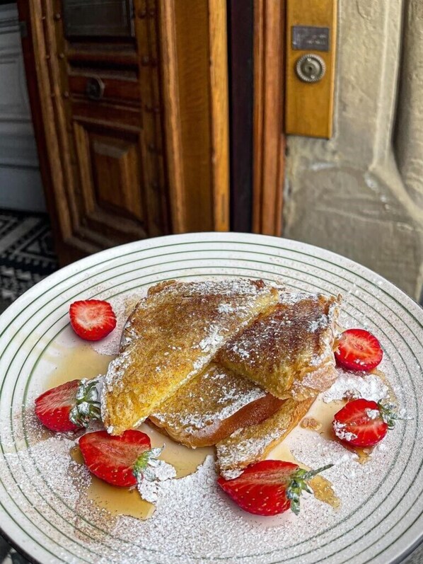 Un plato de pudín de pan con fresas y jarabe, servido sobre un plato a rayas.