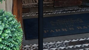 A hotel entrance with a menu board, a chandelier, and a patterned floor. - The Parrs Bank Hotel  (Warrington)