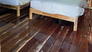 A room with two wooden beds, a wooden floor, a thatched roof, and an air conditioning unit. - Paraiso Cocoyito Ría  (Progreso)