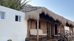 A thatched-roof structure with a wooden deck and a single chair. - Paraiso Cocoyito Ría  (Progreso)