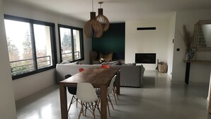 Ein zeitgemäßer Wohnraum mit Essbereich, einer Couch und einem Kamin.