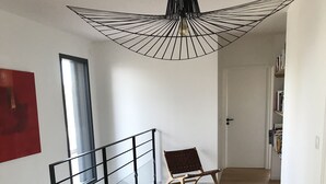 Ein geräumiger Raum mit Holzboden, einer schwarzen Metalltreppe, einem roten abstrakten Gemälde und einer Deckenleuchte.