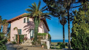 A pink villa with a stone staircase, palm trees, and a view of the sea. - Agrume Country House 8 Emma Villas (Santa Venerina)