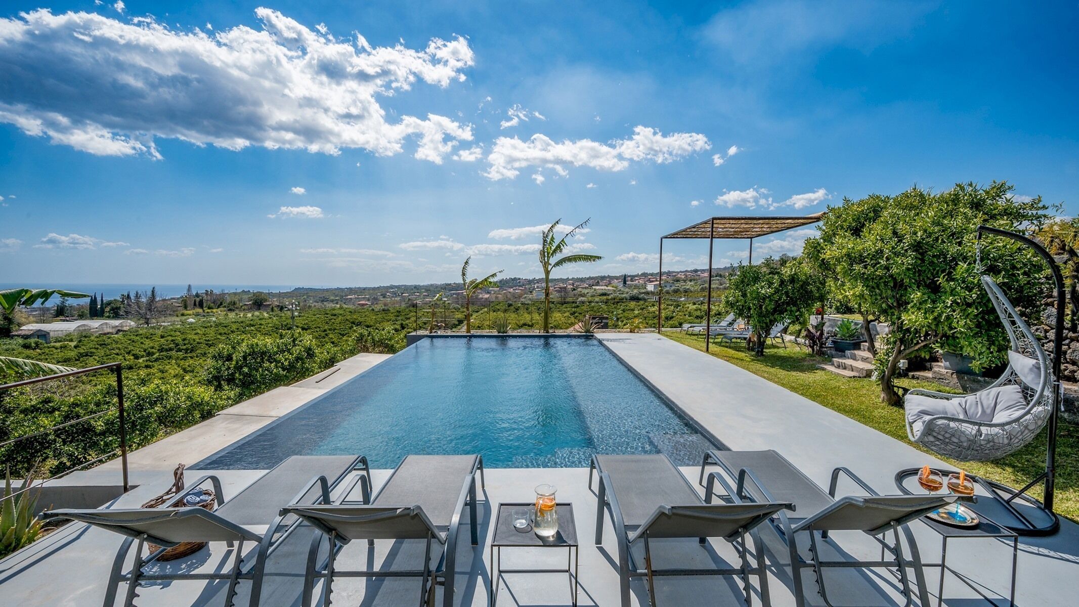 A rectangular pool with a clear blue sky and distant landscape.