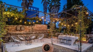 An outdoor patio with stone walls, string lights, and tables set for dining. - Agrume Country House 8 Emma Villas (Santa Venerina)