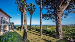 A villa with a terrace overlooking a garden with tall trees and a view of the sea. - Agrume Country House 8 Emma Villas (Santa Venerina)