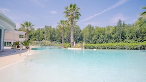 A clear blue pool surrounded by palm trees and a white building. - 5 Relais du Lac Village - Italian Homing (Desenzano del Garda)