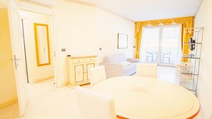 Relax in this stylish room with a round dining table, two chairs, a sofa, and a cabinet, all set against a large window with a view.