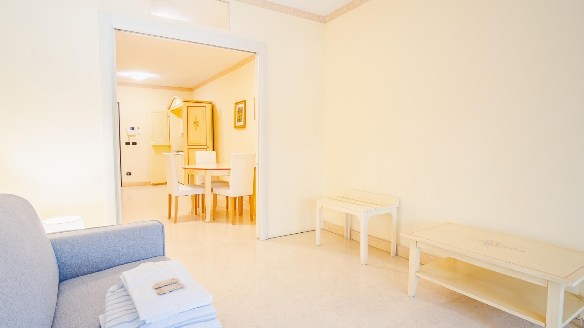 Una sala de estar luminosa y minimalista con un sofá, una pequeña mesa y un comedor con sillas y una mesa.