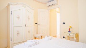 A hotel room with a bed, a small bedside table with a lamp, a chair, and a wardrobe with floral designs. - 2 Relais du Lac Village - Italian Homing (Desenzano del Garda)