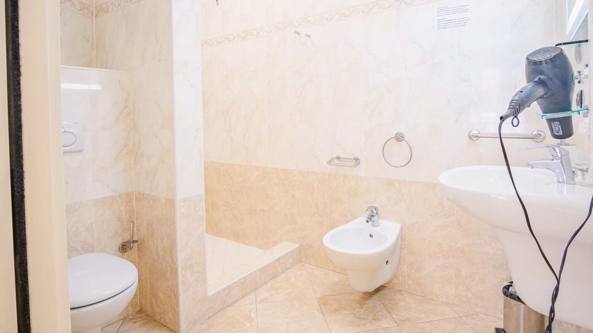 Ein Badezimmer mit Toilette, Bidet und einer Duschkabine aus Glas.