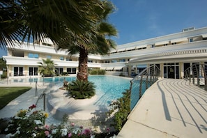 Un hôtel doté d’une piscine entourée de palmiers et de fleurs.