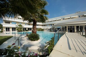 A hotel with a swimming pool surrounded by palm trees and flowers. - 121 Relais du Lac Village - Italian Homing (Desenzano del Garda)