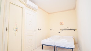 A small, single-bed room with a white door, a small bedside table, and a wall-mounted shelf. - 121 Relais du Lac Village - Italian Homing (Desenzano del Garda)