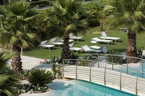 Ein Poolbereich mit Liegestühlen und Palmen.