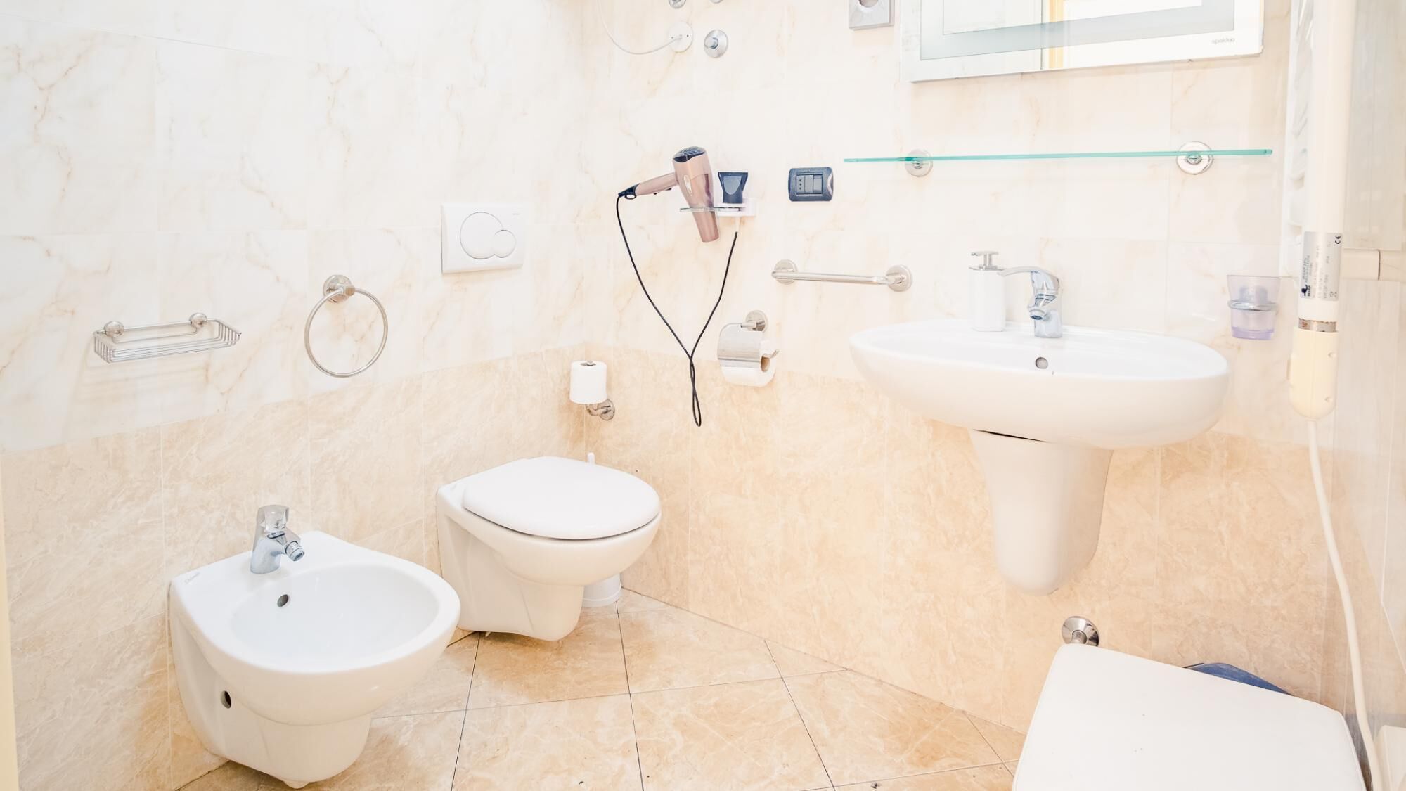 Une salle de bain équipée d’un bidet, de toilettes, d’un lavabo et d’une douche à parois en verre.
