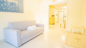 A modern living room with a grey sofa, a small table, and a painting on the wall. - 104 Relais du Lac Village - Italian Homing (Desenzano del Garda)