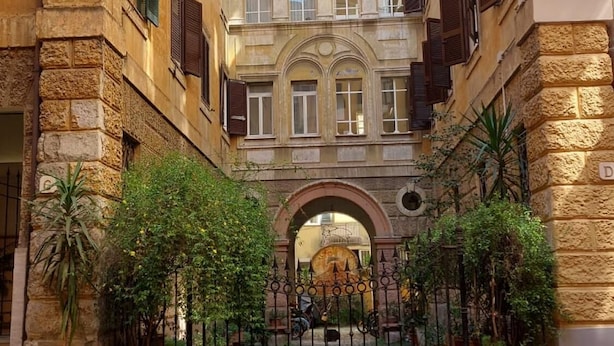 A courtyard with a central archway, surrounded by stone buildings with balconies and windows. - 4bnb - Spacious Porta Pia Apartment (Rome)