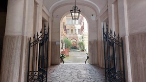An arched corridor with a stone floor, leading to a building with a central archway. - 4bnb - Spacious Porta Pia Apartment (Rome)