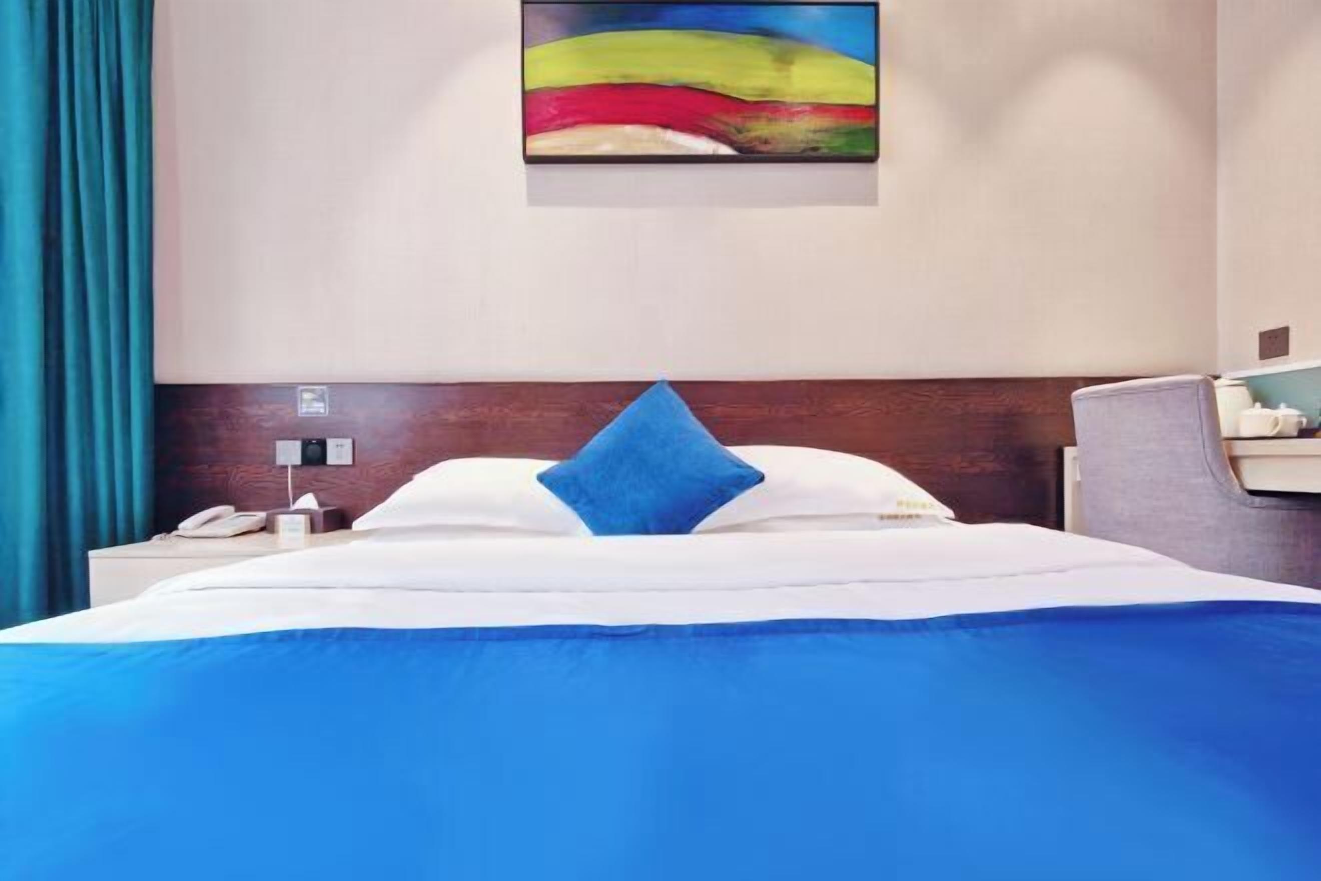 Habitación de hotel con una cama, una mesita de noche, un teléfono y un cuadro en la pared.