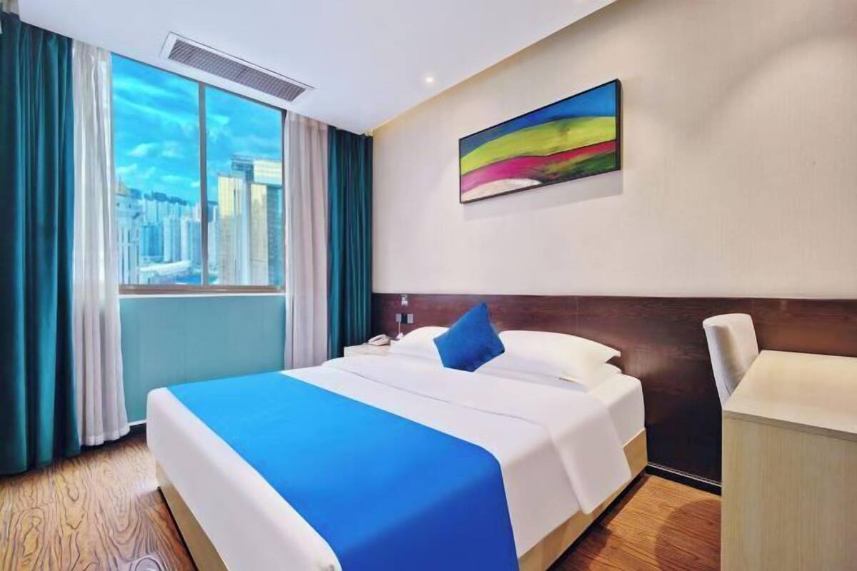 Une chambre d’hôtel avec un grand lit, un bureau et une fenêtre donnant sur la ville.