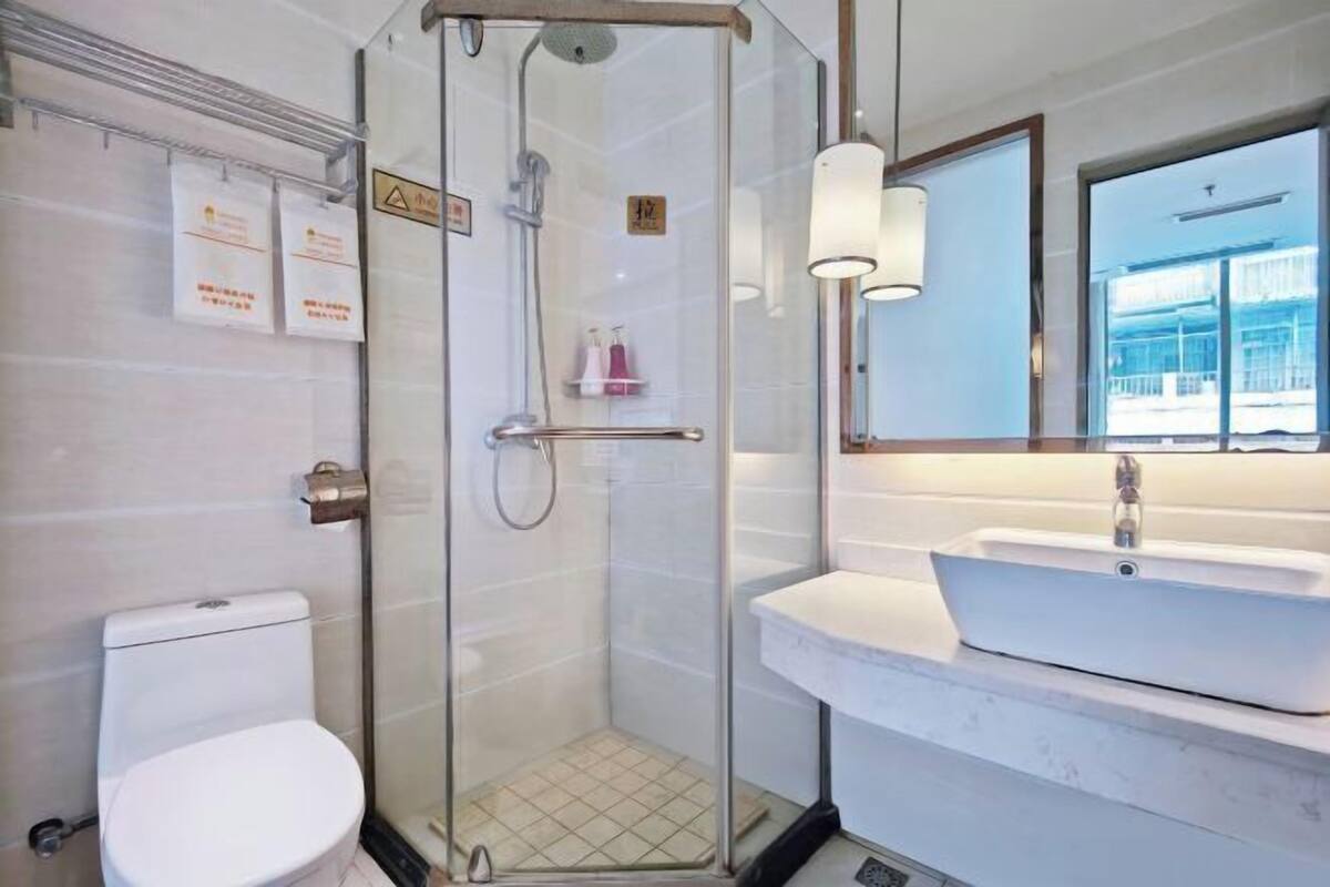Ein modernes Badezimmer mit einer Duschkabine, einem weißen Waschbecken und einer Toilette.