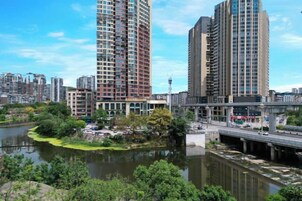 Un río con un puente, rodeado de vegetación y edificios altos.