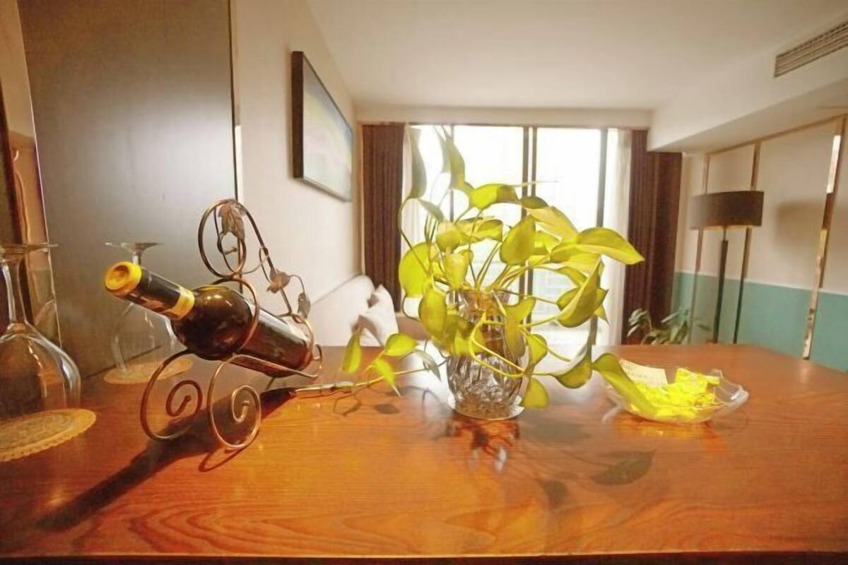 Ein Holztisch mit einer Weinflasche, einer dekorativen Metallskulptur und einer Topfpflanze.