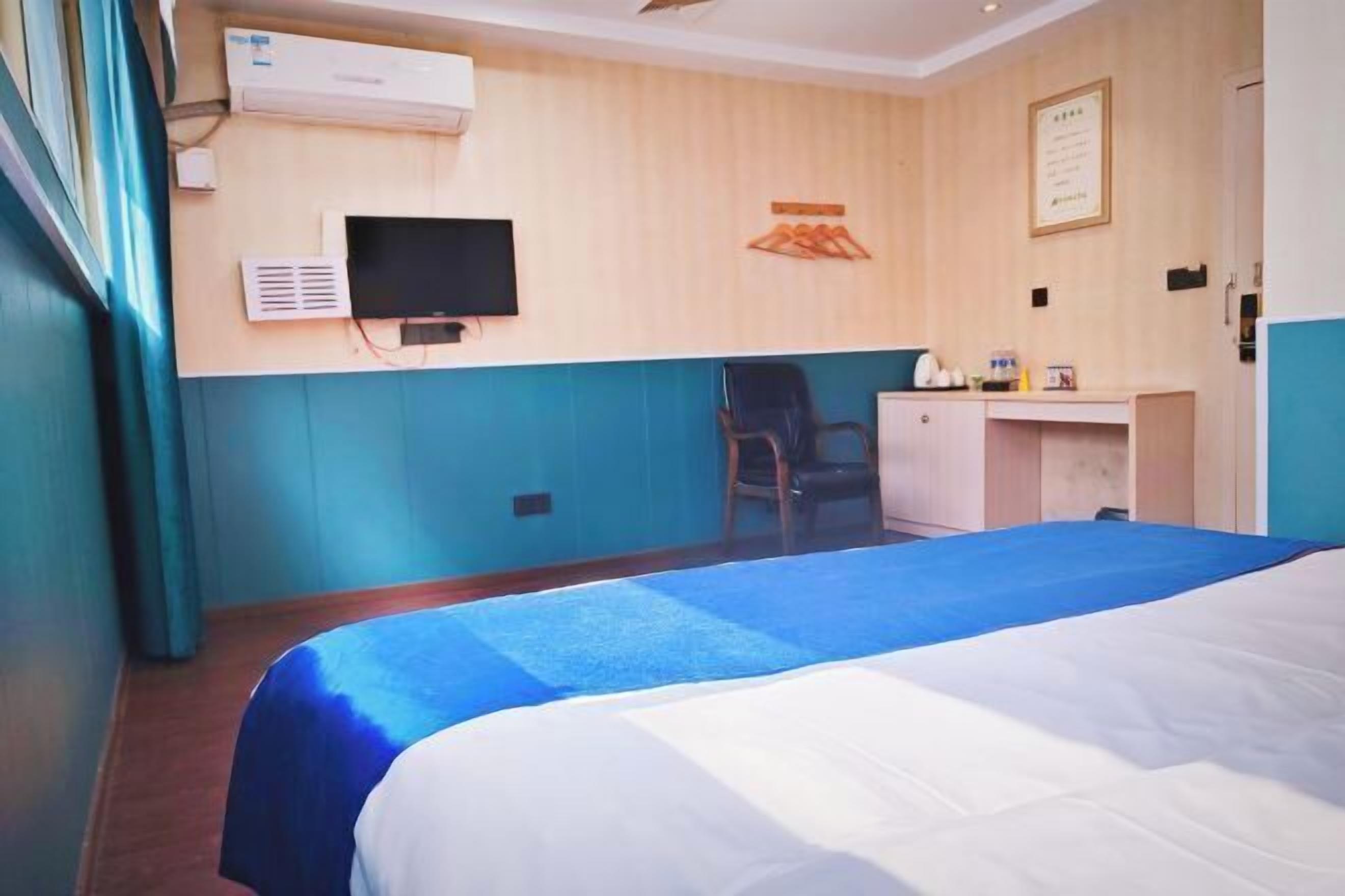 A hotel room with a bed, a desk, a chair, and a television.