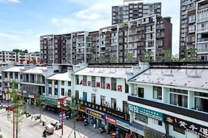 Un edificio de varios pisos con comercios en la planta baja, con señalización de negocios y una calle despejada al frente.