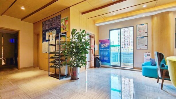 Een hotel lobby met een houten vloer, een potplant, een schoenenrek en een zithoek met stoelen.