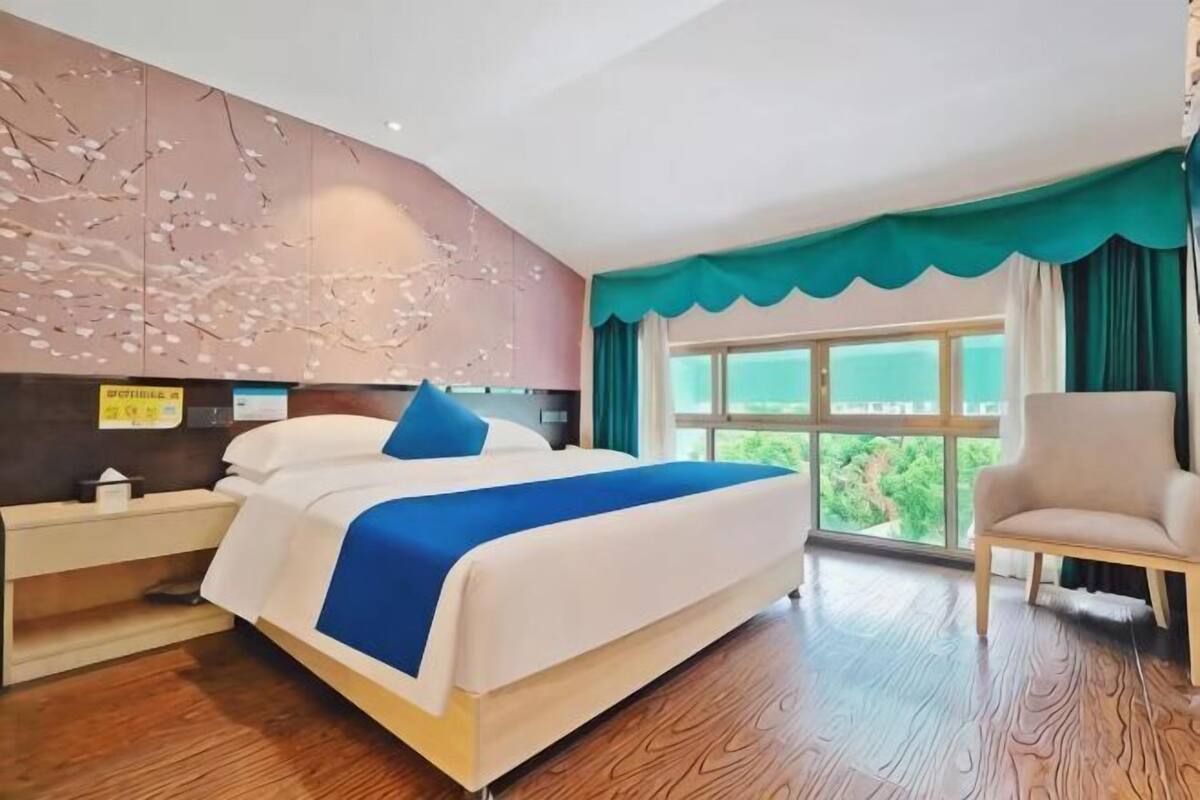 Une chambre d’hôtel avec un lit, une chaise, une table de chevet et une fenêtre donnant sur un paysage agréable.