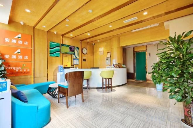 A hotel reception area with a reception desk, seating area, and a large potted plant.