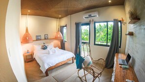 A bedroom with a bed, bedside table, lamp, chair, laptop, and an air conditioning unit. - Happiness Hostel Siargao (General Luna)